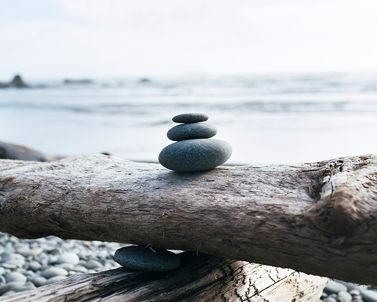 Stapel stenen op balancerende houten stammen op een strand