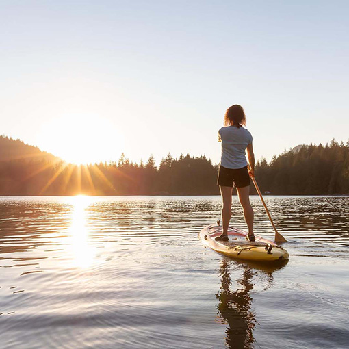 Vrouw op een paddle board op een meer het avontuur tegemoet 